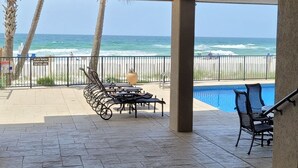 Ein überdachter Außenbereich mit Pool, Liegestühlen und Blick auf den Ozean.