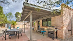 Un patio exterior con zona de estar cubierta, una parrilla y una mesa con sillas.