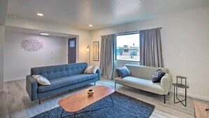 Una sala de estar moderna con dos sofás, una mesa de centro y vistas al exterior a través de un ventanal.