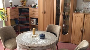 A dining area with a round table, four chairs, a chandelier, a wooden cabinet with glass doors, and a bookshelf. - Bunte Stadt an der Elde (Grabow)