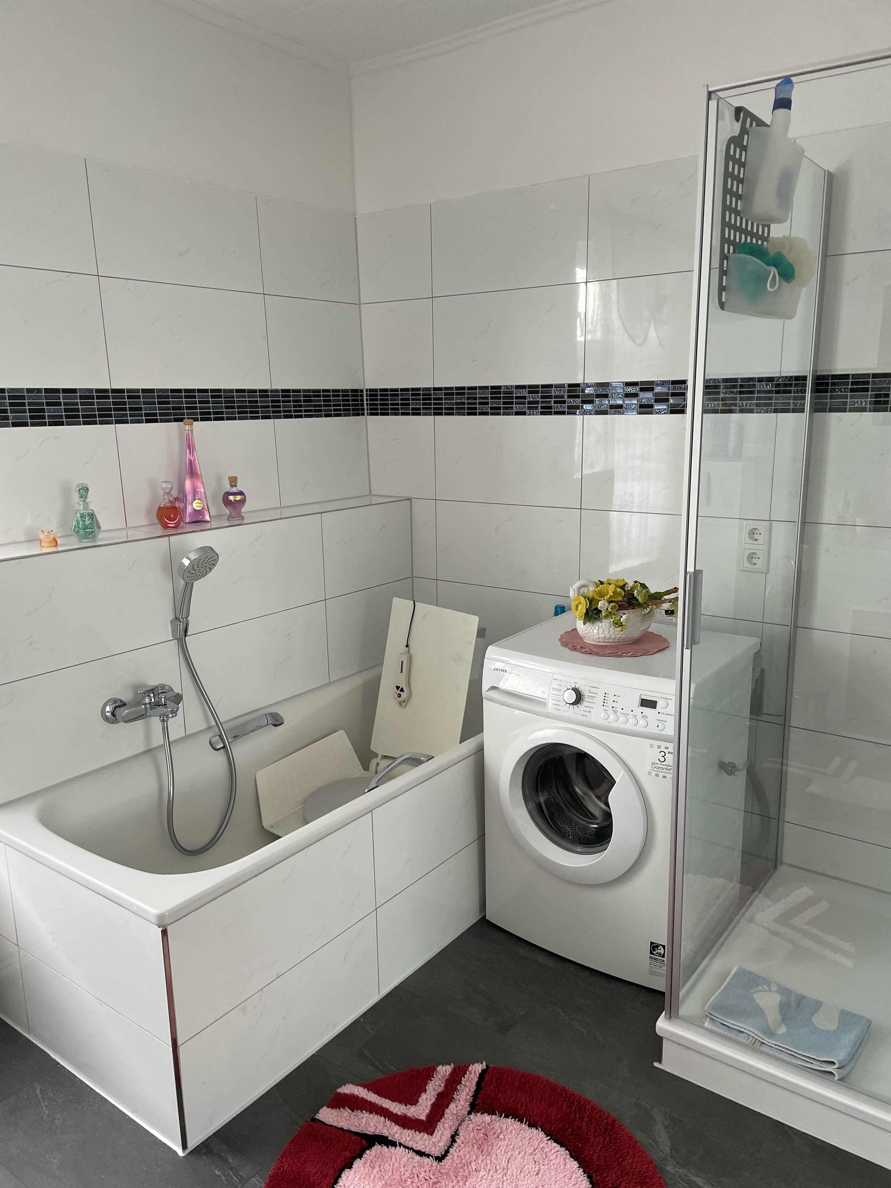 Une salle de bain moderne équipée d’une baignoire, d’une douche à parois de verre, d’un lave-linge et d’un pare-feu en carrelage.