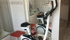 A stationary exercise bike in a bathroom with a tiled floor, a shower area, and a towel rack. - Bunte Stadt an der Elde (Grabow)