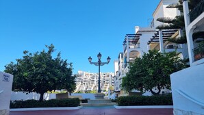 A pathway leading to a pool area with steps and a lamp post, surrounded by white buildings with balconies and trees. - Relax your mind (Mijas)