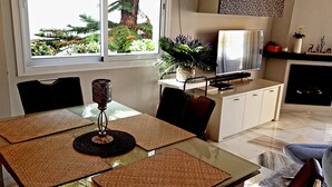 A modern living room with a glass dining table, a TV, and a fireplace. - Relax your mind (Mijas)