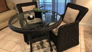 A round glass table with wicker chairs, a potted plant, and a candle on the table. - Quiet Studio, minutes from Beaches, Shopping, Dining, 5th Ave and 3rd Street (Naples)
