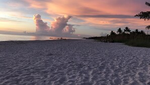 A beach with a wide sandy area, a calm sea, and a sunset sky with clouds. - Quiet Studio, minutes from Beaches, Shopping, Dining, 5th Ave and 3rd Street (Naples)
