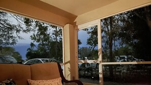 A cozy room with a sofa, a table with a candle, and a view of parked cars and trees outside. - Quiet Studio, minutes from Beaches, Shopping, Dining, 5th Ave and 3rd Street (Naples)
