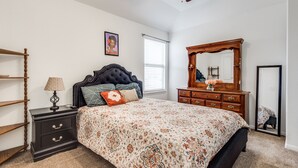 A bedroom with a bed, a dresser, a nightstand, a ceiling fan, and a window with blinds. - Beautiful 2 story luxury home in an upscale area! (Houston)