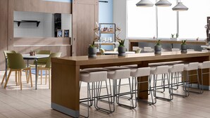 A modern kitchen with a central island, bar stools, and pendant lighting.