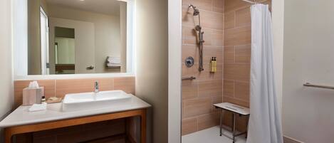 A bathroom with a sink, mirror, and shower.