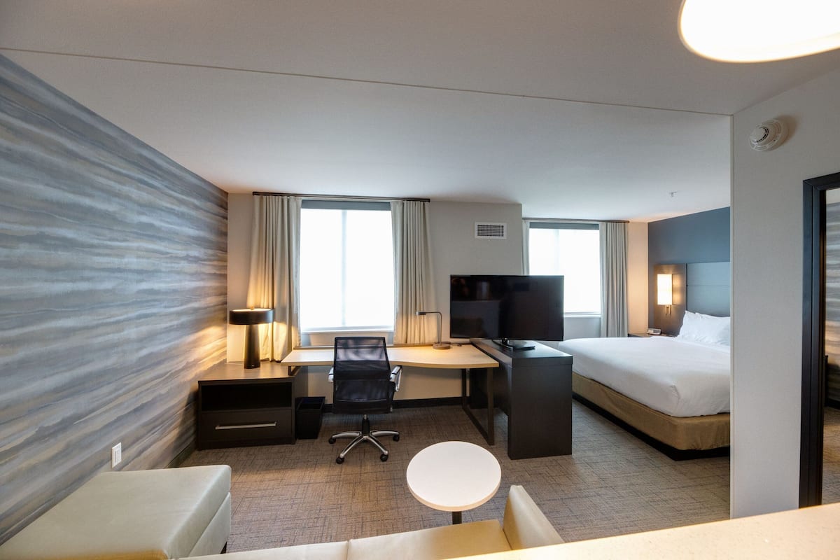 A hotel room with a bed, desk, chair, and a small round table.