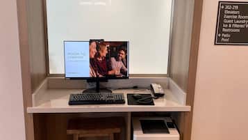 Une chambre d’hôtel équipée d’un bureau, d’un ordinateur, d’une imprimante et d’un petit tabouret.