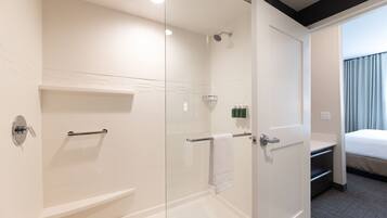 A modern bathroom with a glass-enclosed shower, a white bathtub, and a visible towel rack.