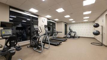 A gym with treadmills, elliptical machines, and a wall with motivational text.