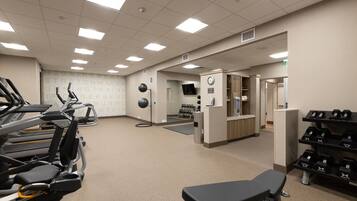 A gym with treadmills, a bench, and dumbbells.