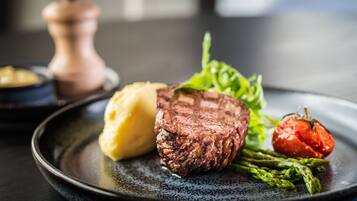 En tallerken med steak, mos kartofler, asparges og en grillet tomat.