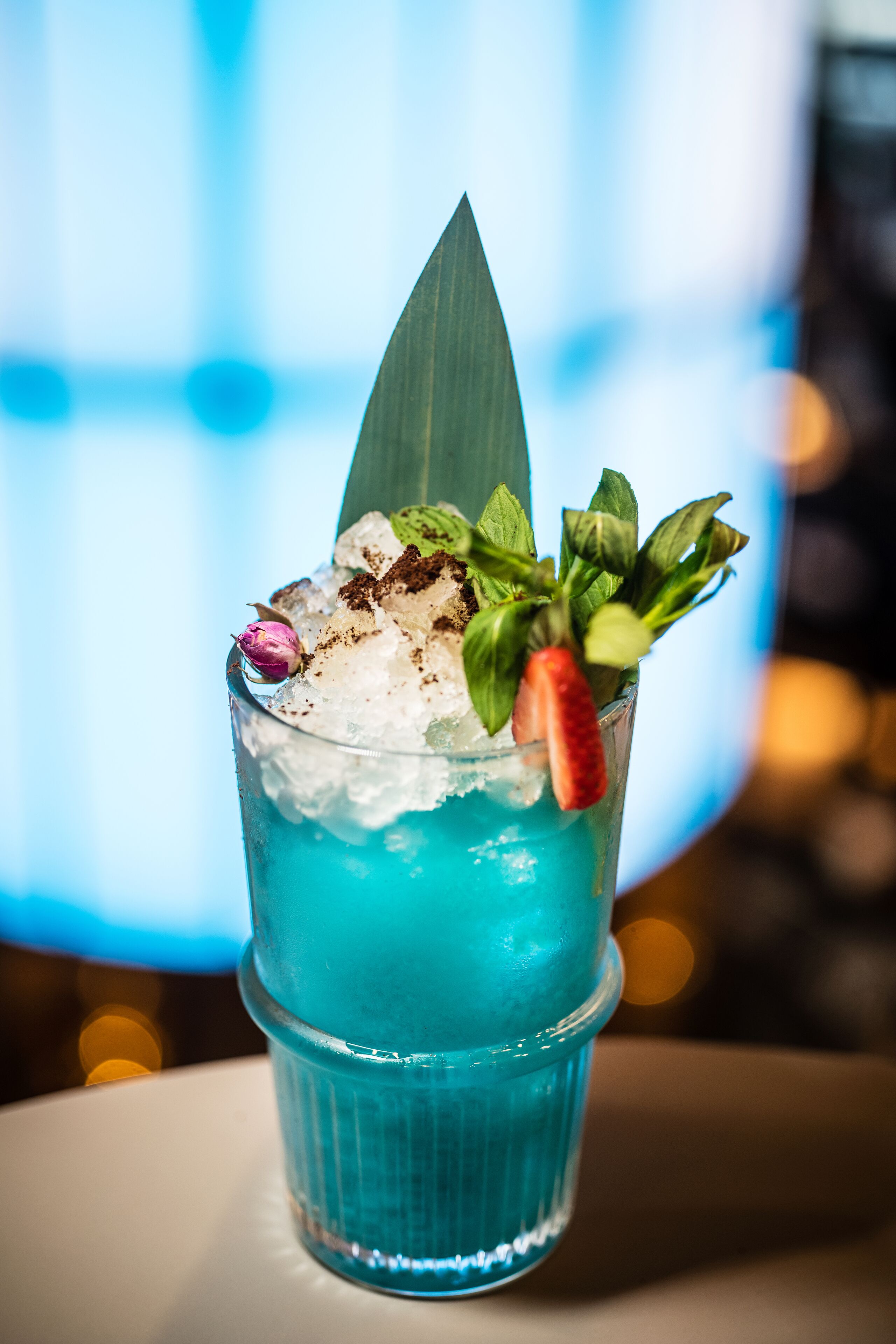 Ein Cocktail mit Eiswürfeln, einer Erdbeere und Minzblättern im Glas.