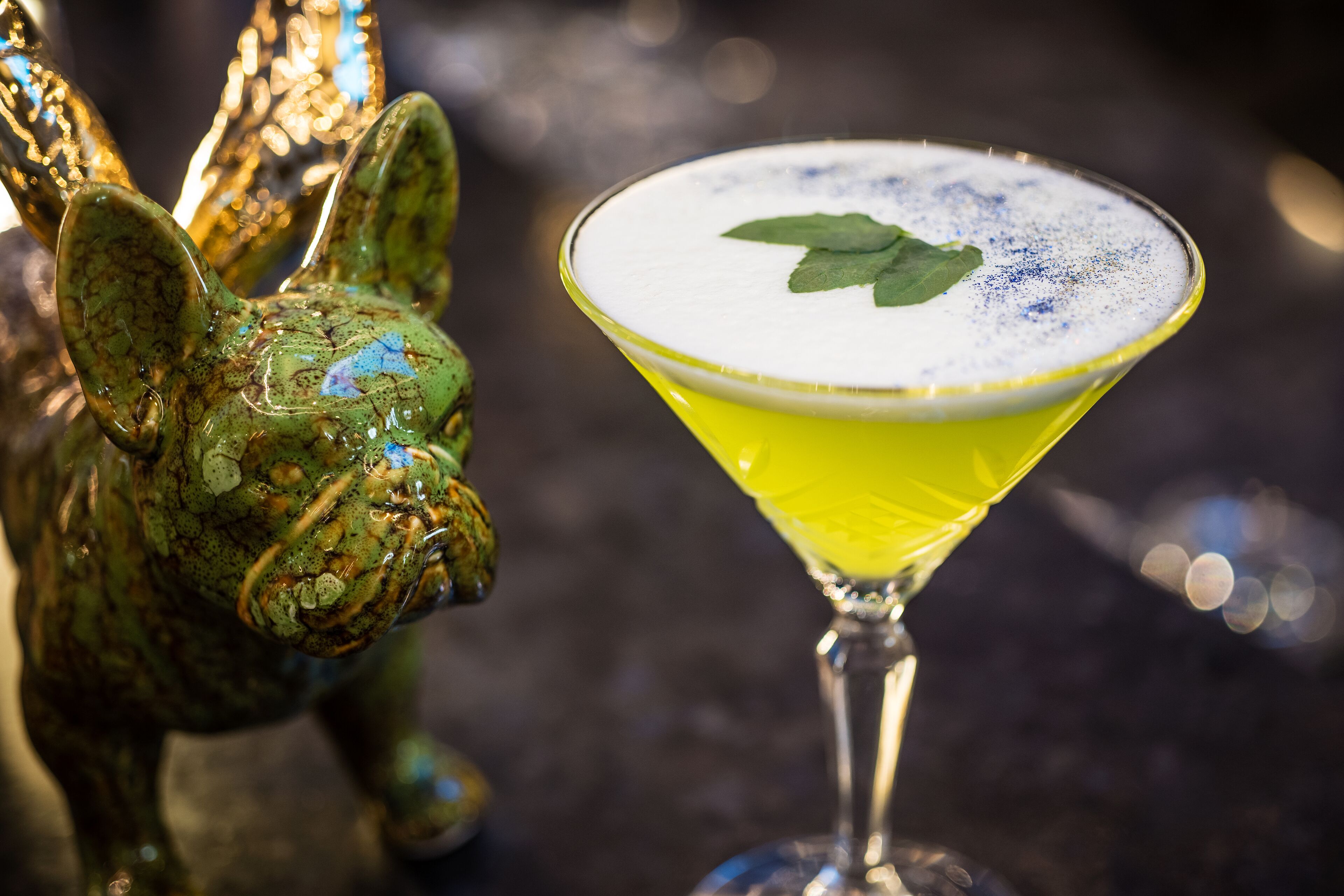 Ein Cocktail im Martiniglas mit schaumiger Oberfläche und einer Minze als Garnitur.