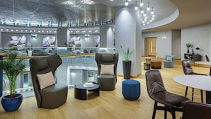 Un área de lounge moderna con asientos de cuero, barandilla de cristal y una mesa de centro.