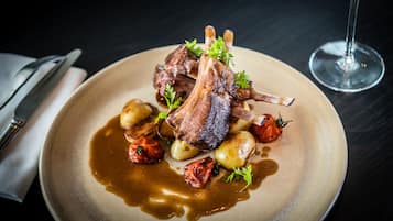 Um prato de comida com carne assada, batatas e um copo de vinho.