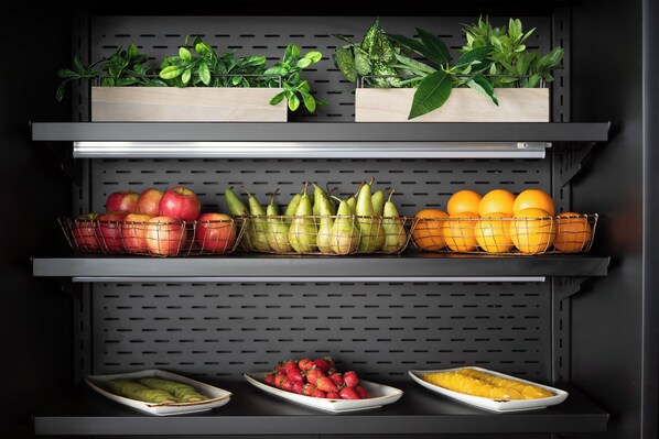 A kitchen with shelves holding fruits, vegetables, and potted plants.