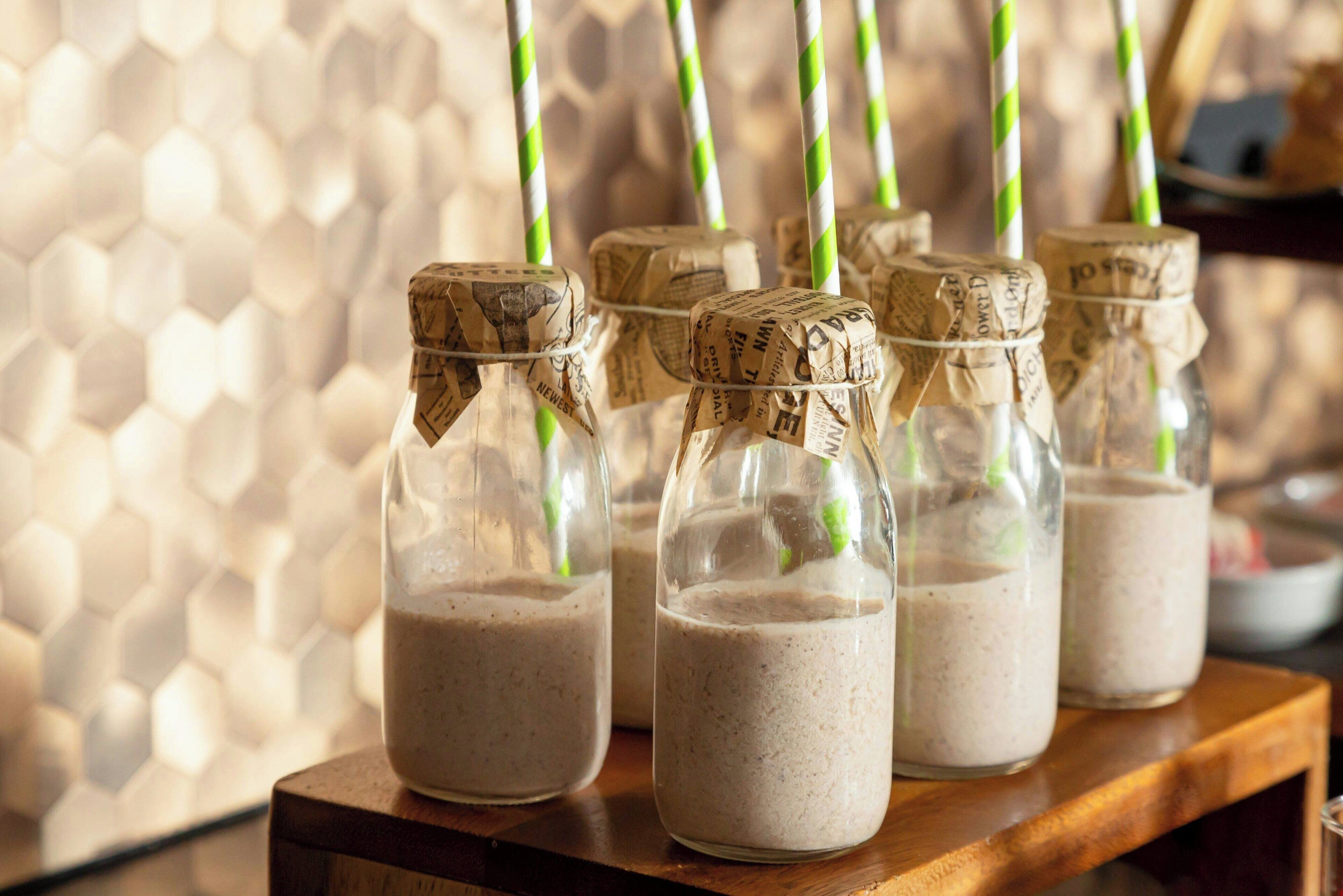 Several glass bottles with cork stoppers filled with a beverage, placed on a wooden surface.