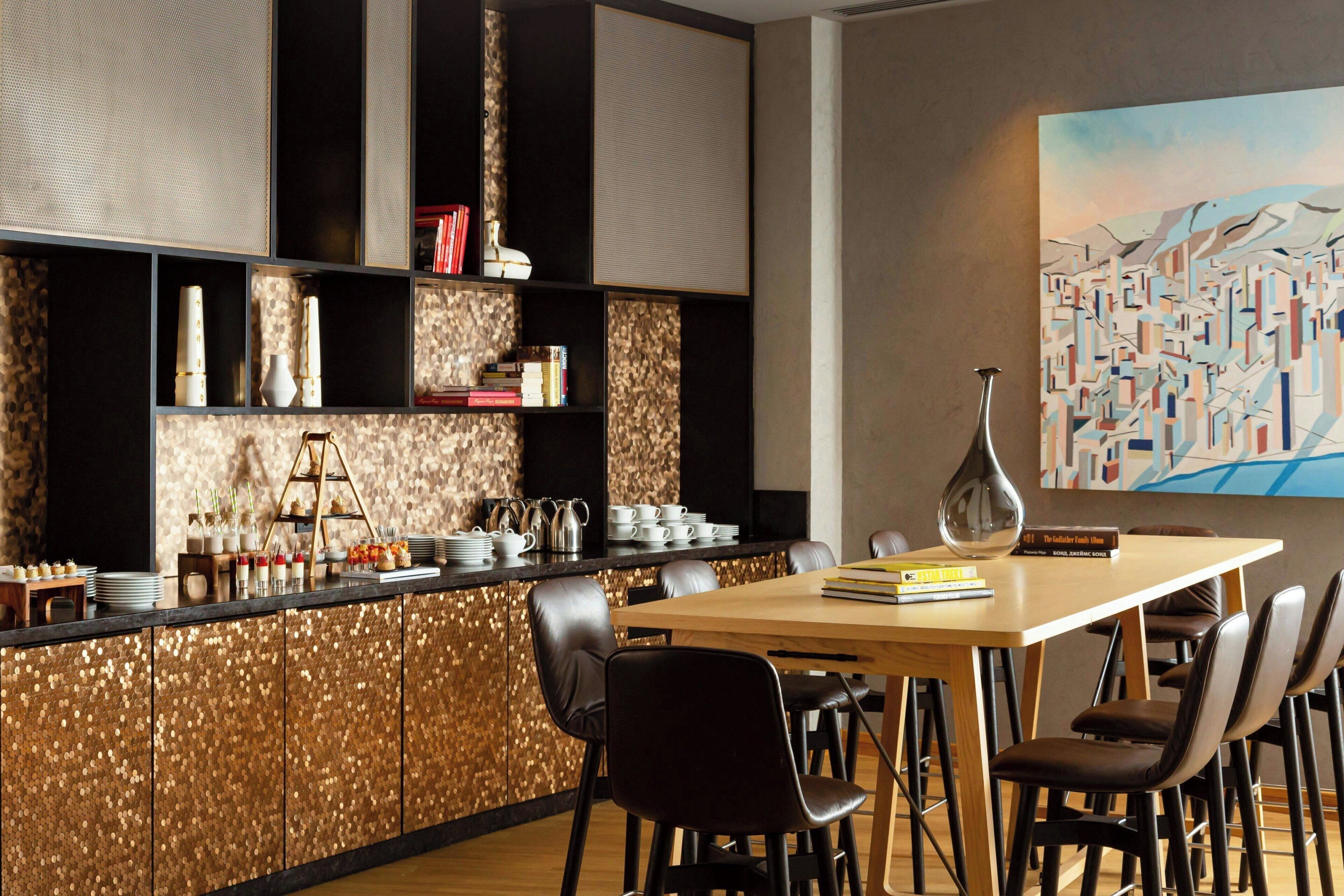 Un espace repas moderne avec une table en bois, des chaises noires, un vase décoratif et une bibliothèque contenant des livres et des objets décoratifs.