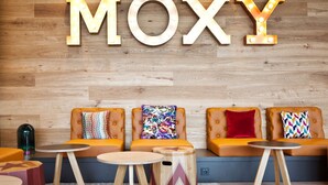Un área de estar con pared de madera y letras iluminadas que dicen "MOXY".