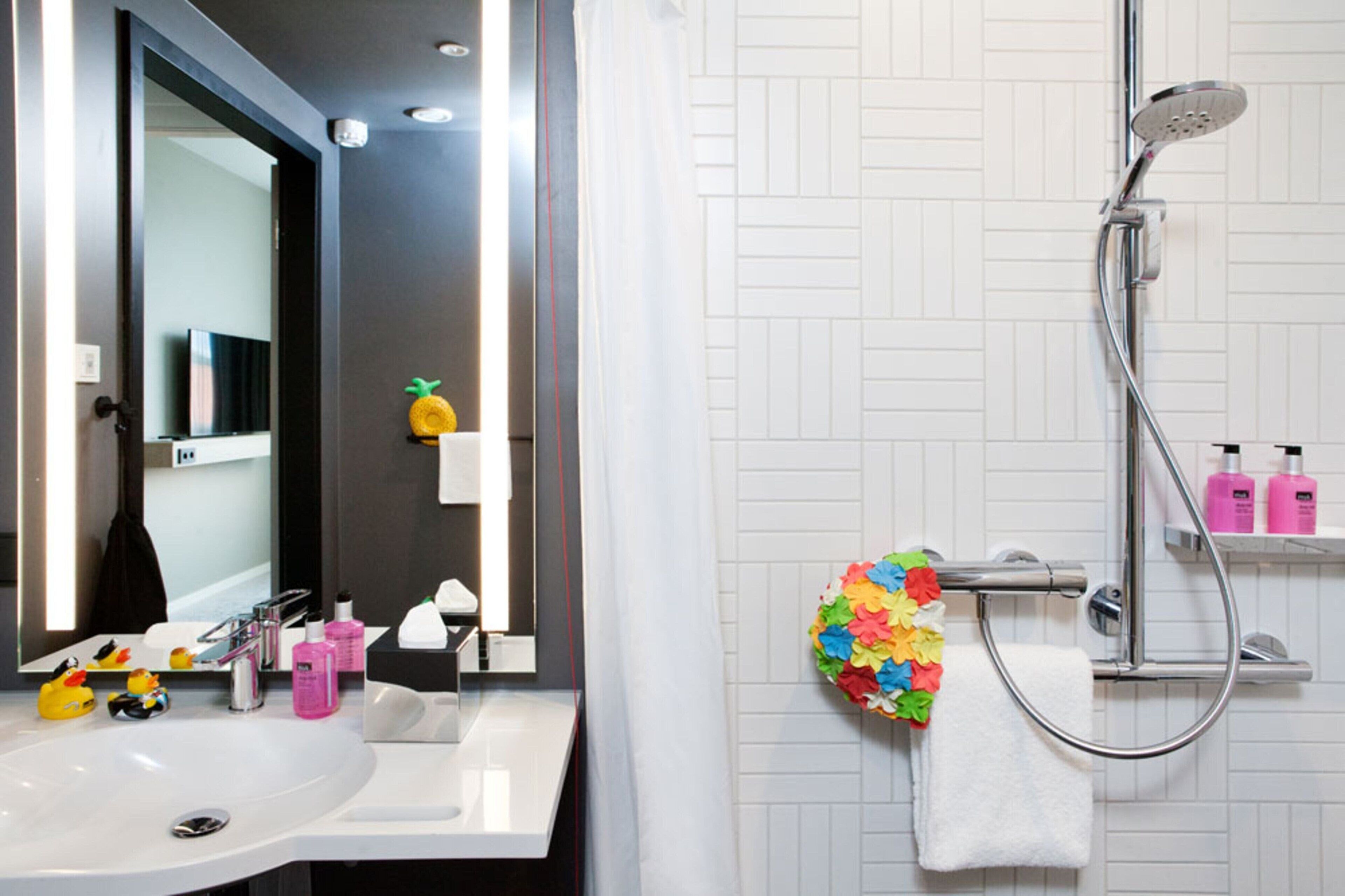 A bathroom with a white sink, mirror, and shower.