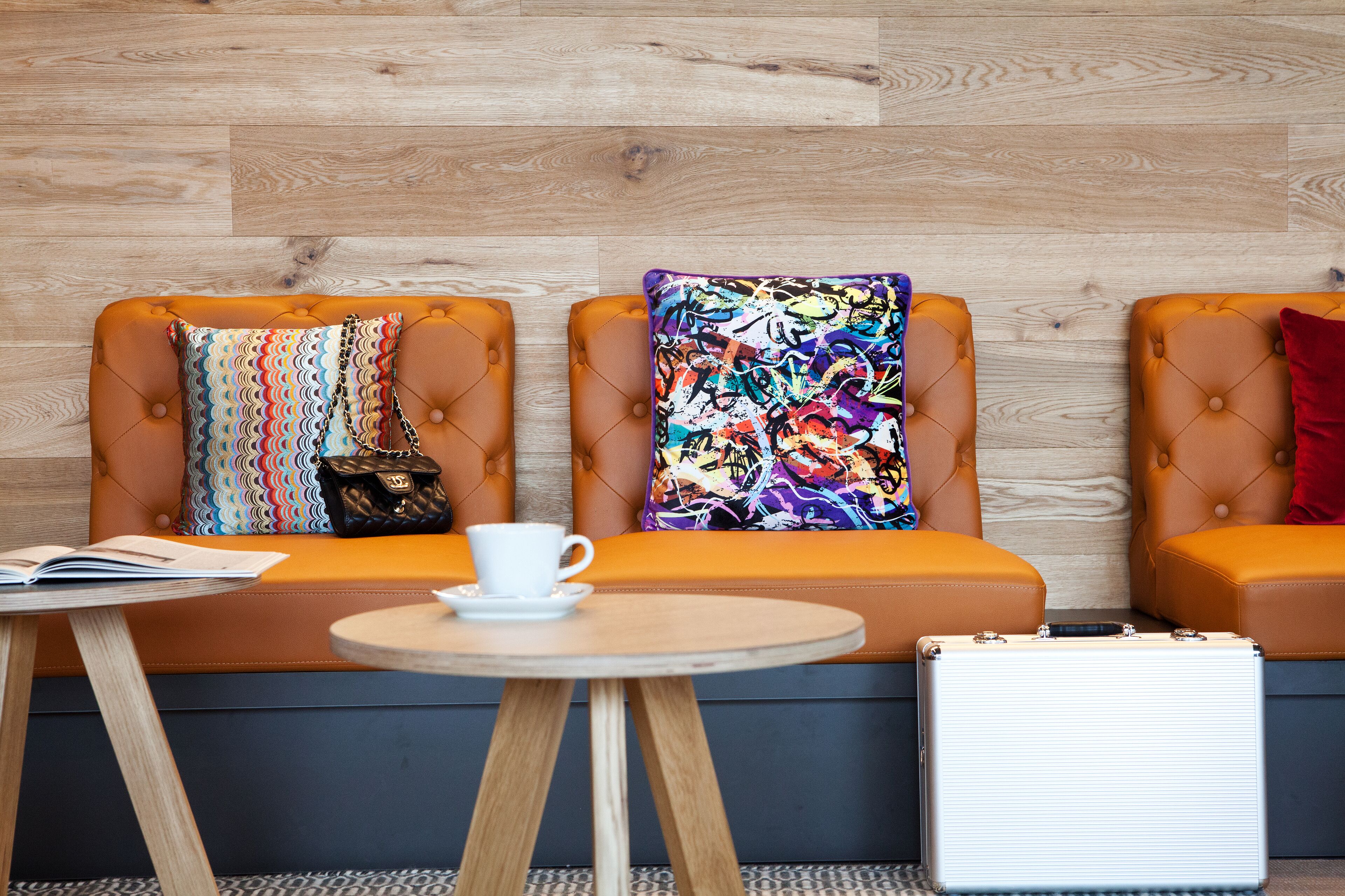 A seating area with cushioned benches, a small table with a cup and a book, and a suitcase.