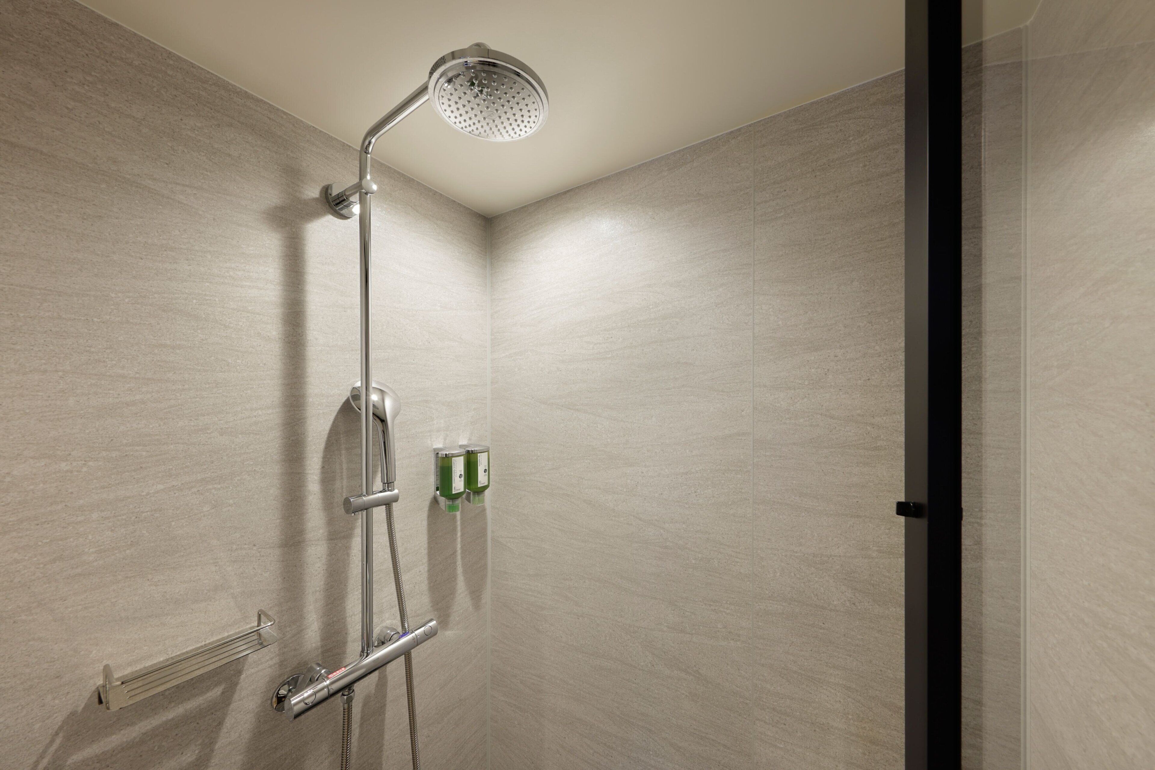 A shower with a handheld showerhead, a handheld showerhead, and a handheld showerhead.