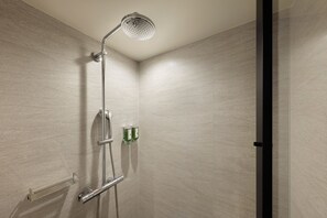 A shower with a handheld showerhead, a handheld showerhead, and a handheld showerhead.