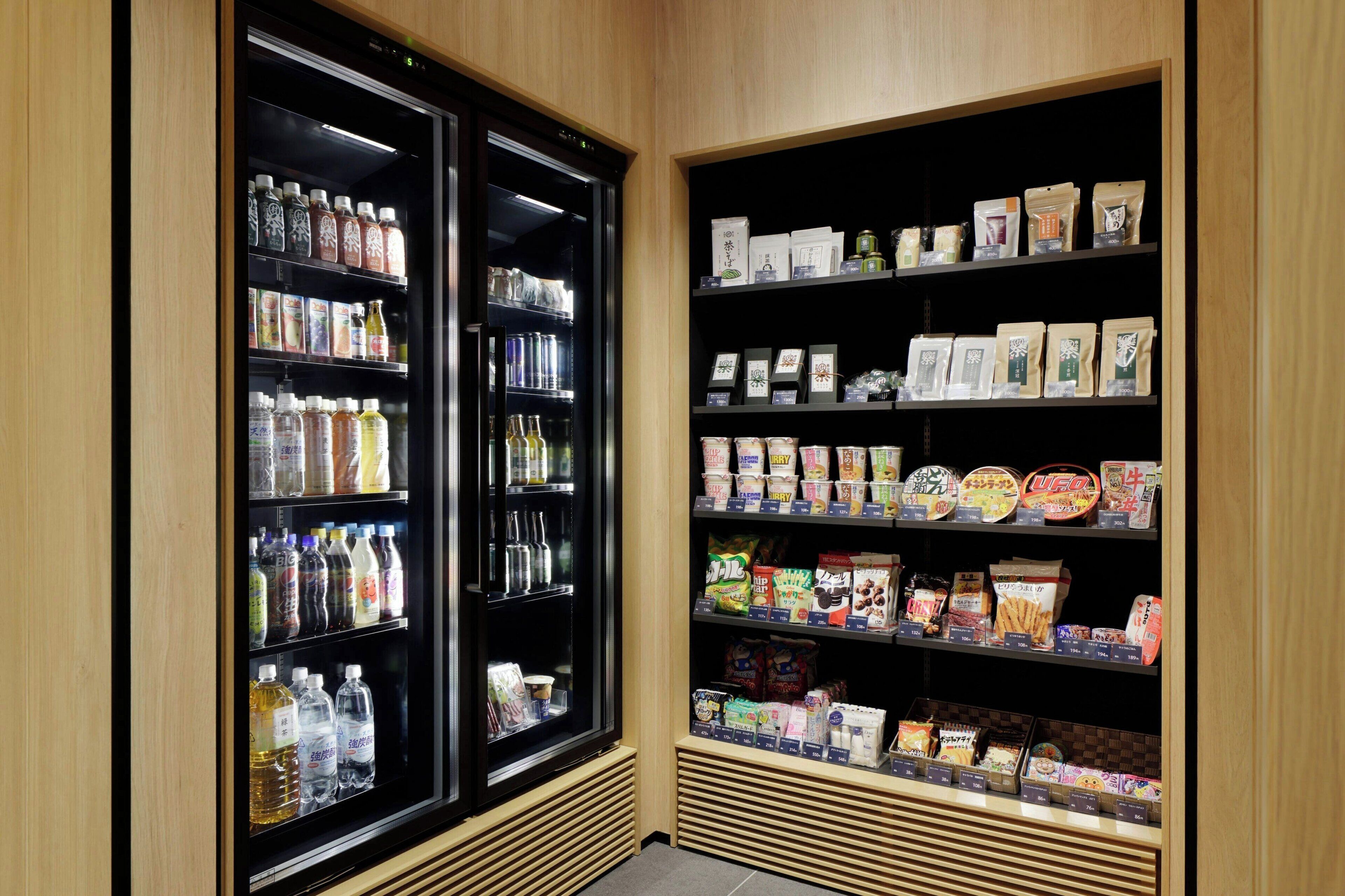 Un distributeur de boissons réfrigéré et des étagères remplies d’en-cas et de produits emballés.