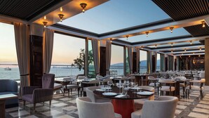 A restaurant with a view of the water, featuring tables and chairs arranged for dining.