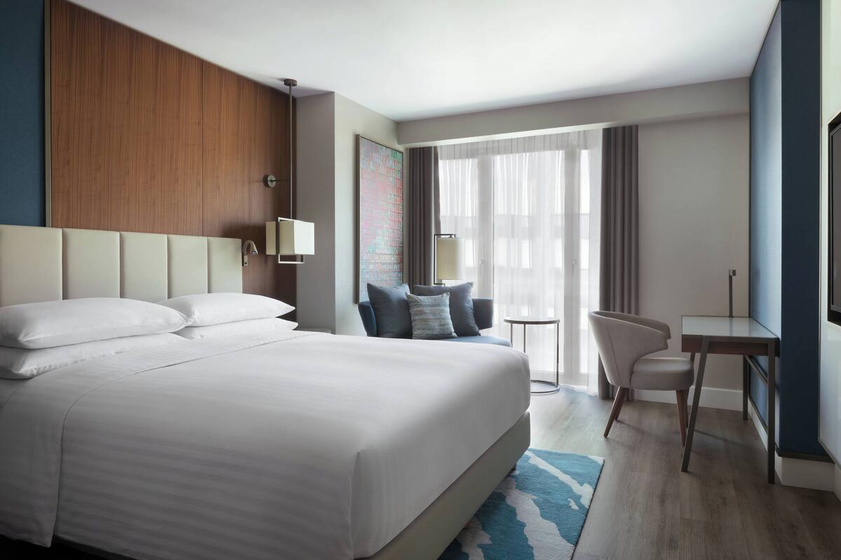 A modern hotel room with a large bed, a desk, and a chair.