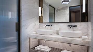 A modern bathroom with two sinks, a large mirror, and a towel rack.