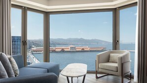 A spacious room with a large window offering a view of a body of water and distant mountains.
