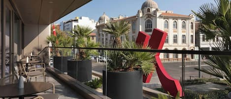 Un balcon avec un espace salon extérieur, des plantes en pot et une vue sur un bâtiment historique doté de coupoles.