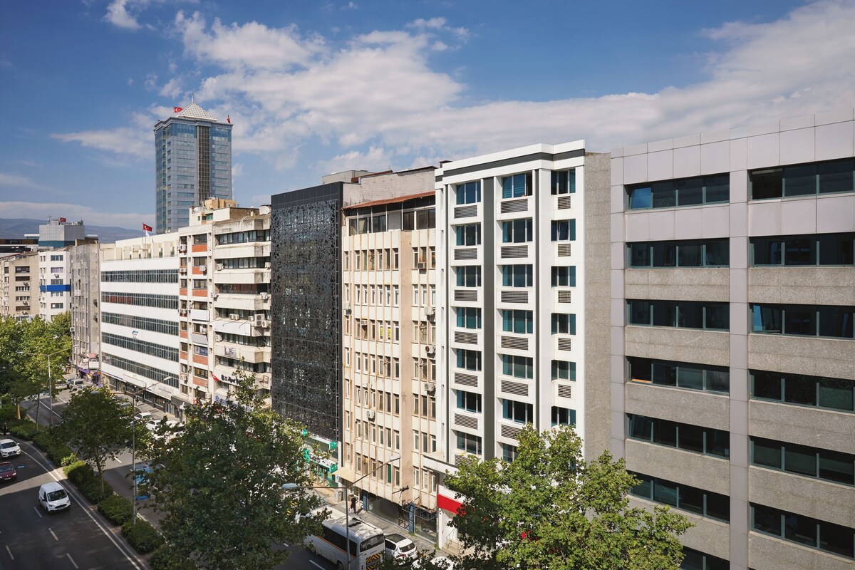 Een modern complex van stadse gebouwen met meerdere hoge torens, waaronder een opvallend glazen wolkenkrabber.