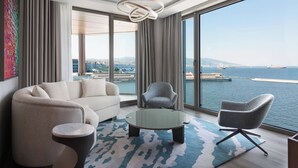 A modern living room with a sofa, armchairs, a coffee table, and a view of the sea.
