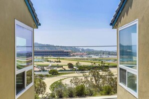 Blick vom Balkon durch große Fenster auf ein Sportgelände und ein Gewässer.