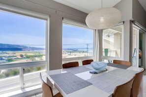 A dining area with a table, chairs, and a view of a bridge and landscape.