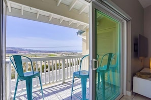 A balcony with two chairs and a view of a bridge.