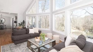 Ein geräumiges Wohnzimmer mit einer großen Eckcouch, einem Glastisch und Seeblick durch große Fenster.