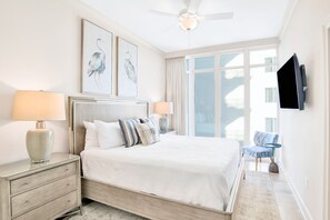 A hotel bedroom with a large bed, a nightstand with a lamp, a chair, and a TV mounted on the wall. - Phoenix Orange Beach II 805 | Endless Views, Lazy River, Luxury! (Orange Beach)