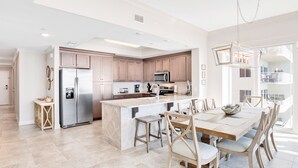 Une cuisine moderne dotée d’un îlot central, d’appareils électroménagers en acier inoxydable et de meubles de rangement en bois.