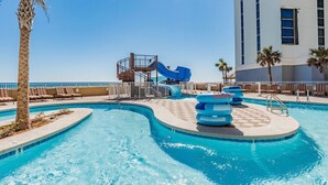 Une piscine avec un toboggan, des chaises longues et des palmiers.
