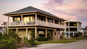 A two-story house with a balcony, a covered porch, and a flag.