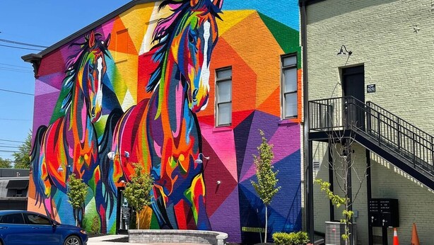 Un edificio con un mural vibrante de caballos en su fachada.