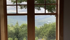 Una ventana con vistas a un paisaje montañoso y un florero en el alféizar.